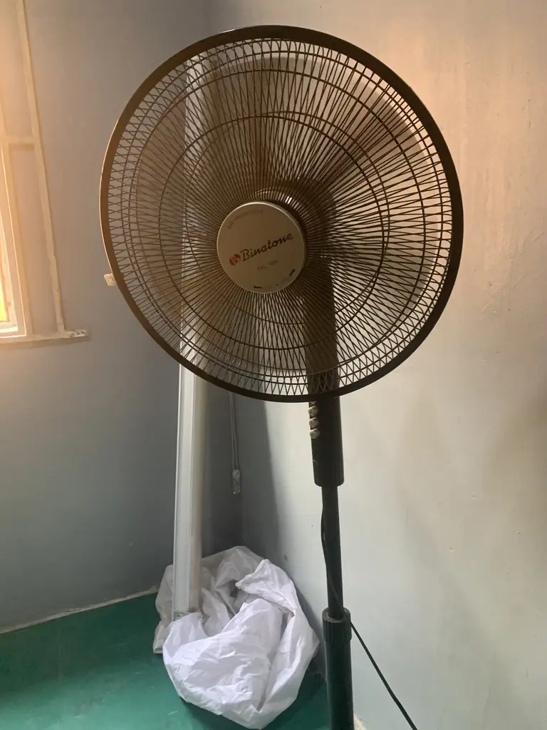 Standing Binatone Fan’ A bag, table and chair and laptop